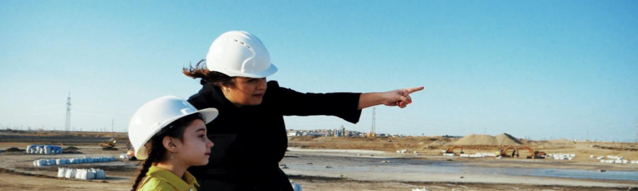 Woman and young girl wearing hard hat in construction site