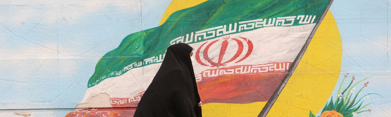A woman walking in front of Iran flag
